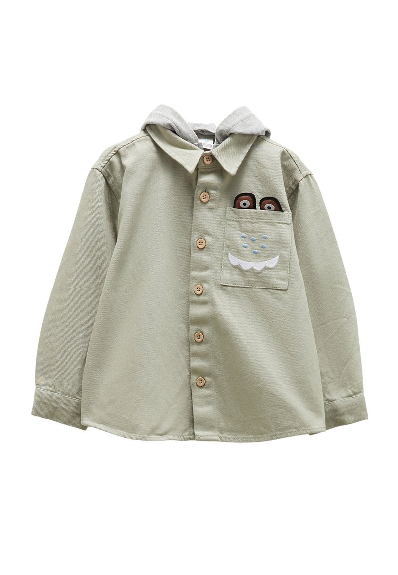 Světle zelená košile na knoflíky s šedou mikinou. Má dřevěné knoflíky a přední kapsu s vyšitými detaily postavy.
