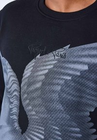 Schwarzer Pullover mit großem grauem Adler-Graphic, strukturiertem Stoff und gesticktem „Project x Paris“-Logo im Brustbereich.