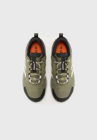 Olive green athletic shoes with a mesh upper, black accents, white side stripes, gray laces, and an orange insole.