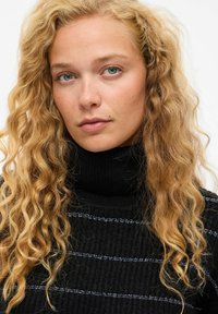 Črna rebrasta turtleneck pulover s srebrnimi horizontalnimi črtami; ima teksturirano pletenje in visok ovratnik.