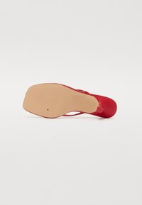 Rød høyhælte sko med et stilrent design, glatt tekstur og en lys beige såle. Har en spiss tå og en slank stiletthæl.