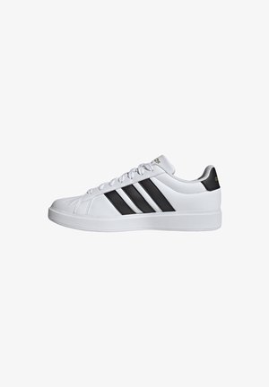 White sneakers with black three-stripe design, smooth synthetic texture, flat sole, and lace-up closure. Gold accent on heel.