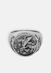 Anello in argento con una fascia circolare texture che presenta un design di pesce in rilievo circondato da onde ondulate e dettagli intricati.