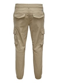 Pantalons cargo beiges en coton, avec de multiples poches latérales et arrière, des poignets élastiques et une coupe décontractée.