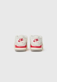 Nike Air tenisice s bijelim kožnim gornjim dijelom, crvenim detaljima i udobnom potplatom. Na stražnjem dijelu prikazan je natpis "NIKE AIR".
