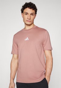 Roze katoenen T-shirt met een ronde hals, korte mouwen en een klein wit logo op de borst. Glad materiaal met een relaxed fit.