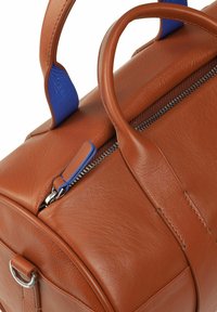 Borsa a tracolla in pelle marrone con dettagli blu, dotata di manici arrotondati, chiusura a zip e una texture liscia. Include dettagli in metallo argentato.