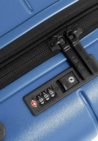 Valise rigide bleue avec deux fermetures éclair noires, surface texturée, serrure à combinaison et caractéristiques de sécurité approuvées par la TSA.