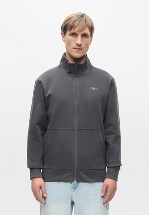 Kullsvart hettegenser med høy krage, to frontlommer og en subtil turkise logo. Myk stoff og avslappet passform.