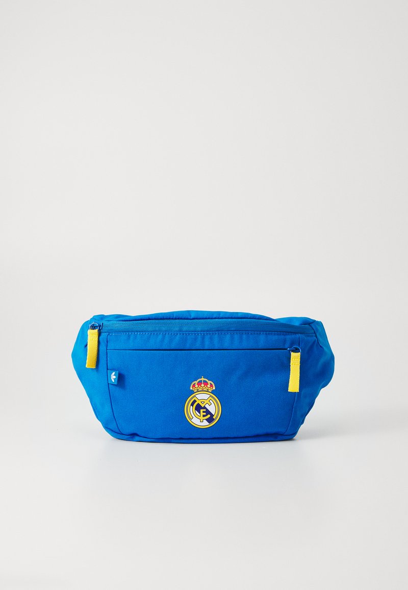 Blåt stoff bumbag med en frontlomme med glidelås, gule glidelåsdetaljer og en fremtredende Real Madrid-logo med krone.