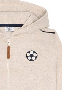 Felpa con zip beige per bambini, con cappuccio, piccola palla da calcio ricamata in blu e bianco sul lato sinistro del petto, tirante della zip con il nome del marchio.