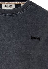 Sweatshirt gris foncé avec un col ras du cou côtelé, présentant un logo noir discret sur la poitrine et un tissu texturé.