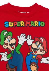 Rotes T-Shirt mit Super Mario Figuren, eine in Grün und eine in Rot, mit bedruckten Grafiken sowie kontrastierenden weißen Handschuhen und Gesichtszügen.