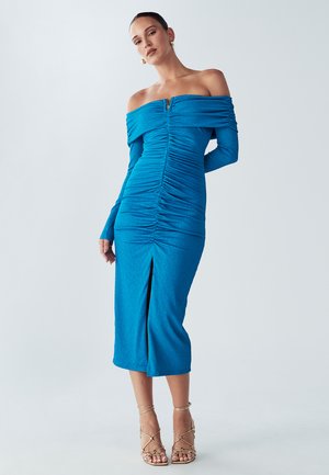 Vestito blu brillante a spalle scoperte con texture arricciata, maniche lunghe e uno spacco frontale, con una dettagliata cerniera dorata sul collo.