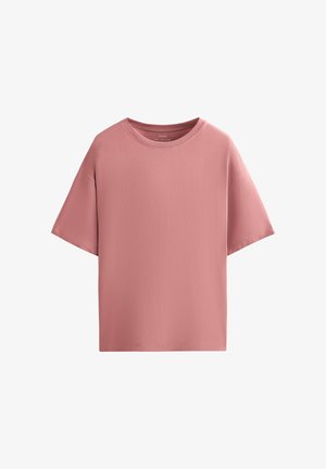 T-shirt oversize à manches courtes de couleur rose pâle avec encolure ronde, design uni, sans logos ni motifs visibles sur fond blanc.