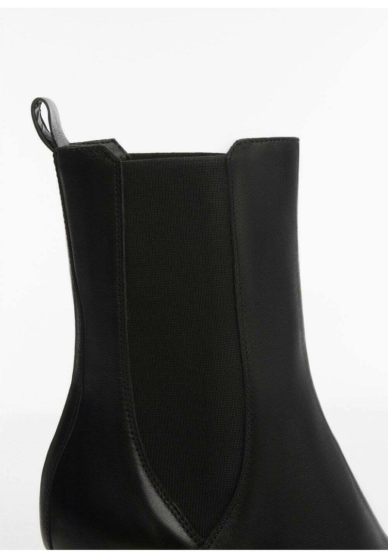 Botín negro de tobillo con cuero suave y paneles laterales elásticos, con una lengüeta en la parte posterior para facilitar la puesta y una silueta elegante.