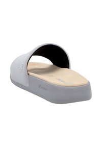Sandale grise à glisser avec une large lanière, semelle plate et semelle intérieure texturée. Présente un matériau doux et un logo discret sur le côté.