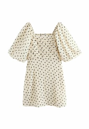 Robe crème à pois noirs, manches bouffantes jusqu'au coude, encolure carrée, et plis horizontaux sur la poitrine.