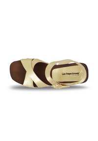 Sandal de color dorado, con tiras y suela de madera, que presenta una hebilla y tiras superiores cruzadas. Textura suave con acabados brillantes.