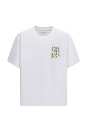 Biała koszulka z krótkim rękawem z małą, kolorową, pionową grafiką abstrakcyjnych kształtów i stylizowanych postaci na lewej piersi.