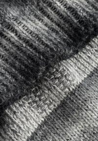 Grauer Strickstoff mit abwechselnd dunklen und hellen Streifen. Die Textur ist weich und hat ein geripptes Muster, das unterschiedliche Garnstärken zeigt.