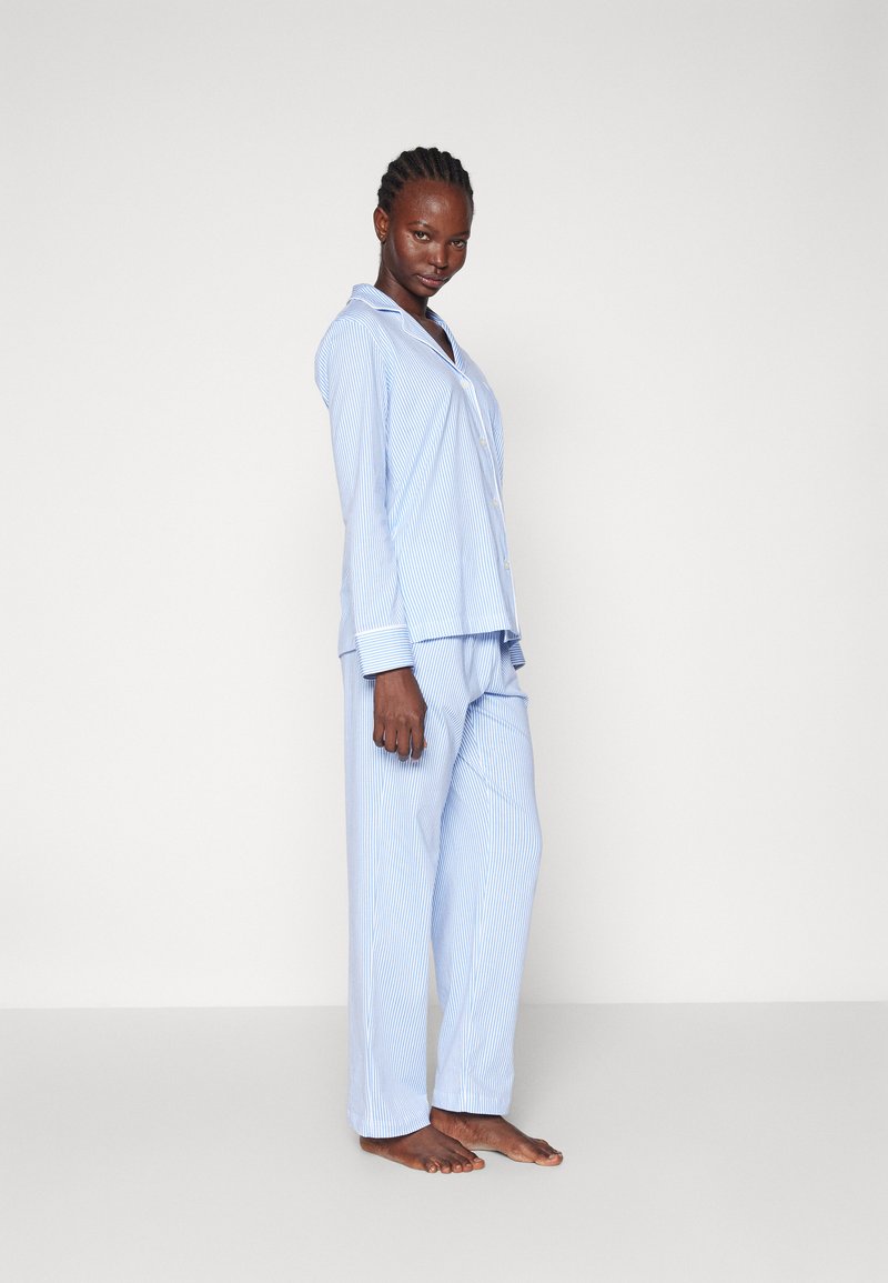 Modra in bela prugasta pižama z dolgimi rokavi in hlačami, ki vključuje srajco z gumbi in mehak tekstil.