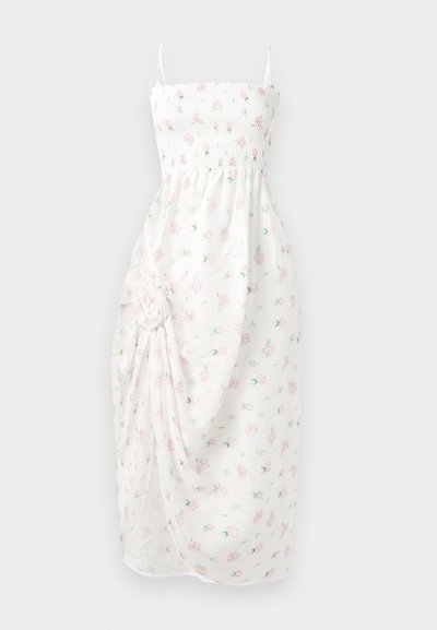 Rochie albă cu bustul plisat, bretele subțiri și imprimeu floral în nuanțe de roz. Prezintă material strâns și detaliu cu nod lateral, precum și fanta.