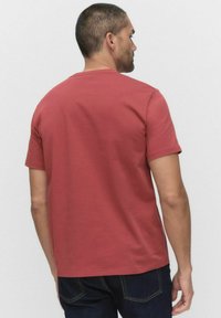 Rød bomulds t-shirt med rund hals og korte ærmer, glat tekstur og et simpelt design. Visning fra ryggen viser krave og skulderstruktur.