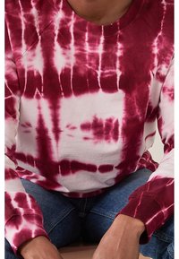 Felpa rossa e bianca tie-dye con maniche lunghe e collo a coste, caratterizzata da un motivo astratto e una morbida texture in cotone.