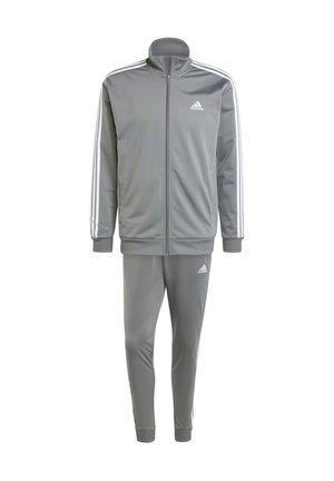 Tuta sportiva grigia realizzata in materiale liscio, con giacca zip-up a colletto alto, polsini a costine e tre strisce bianche sulle maniche e sui pantaloni.