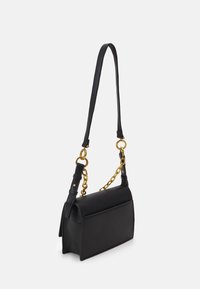 Svart lærveske med en strukturert form, som har et avtagbart kjede-stropp samt en glatt tekstur. Minimalistisk design.