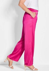 Fuchsia wijde broek met satijnen textuur, voorzien van een elastische tailleband en zijzakken, gecombineerd met een beige sandalen met blokhak.