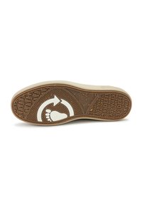 Beige színű gumi talp, texturált barna mintázattal, amelyen láb, kör és aláírás logók találhatók. Gravírozott minták és újrahasznosított anyag részletezése.