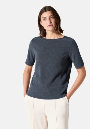 Top de manga corta azul marino con un diseño texturizado y cuello redondo, combinado con pantalones de pierna ancha de color crema.