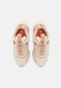 Baskets beige clair avec une tige en maille texturée, accentuées de beige, lacets rose et un logo sur la languette. Semelle en caoutchouc pour une bonne adhérence et un soutien.