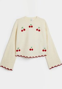 Krämfärgad stickad tröja med röd körsbärsbroderi, vågig nederkant och vida ärmar. Texturerad yta med upphöjda prickar.