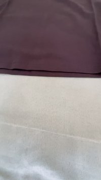 Dvi persidengiančios audinio dalys: tamsiai violetinė tekstūruota medžiaga viršuje ir lygi, šviesiai pilka apatinė dalis. Be raštų ar pastebimos aparatūros.