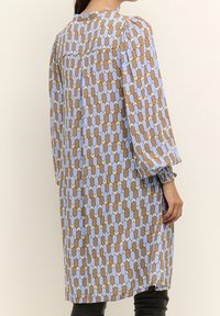 Dlouhé šaty s hnědým a světle modrým hexagonálním vzorem. Vyrobeny z lehkého materiálu s nabíranými rukávy a kulatým výstřihem.