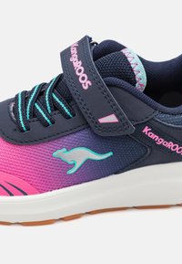 Blue and pink athletic shoe with mesh upper, featuring a velcro strap, kangaroo logo, and textured surface. Rubber outsole for traction.