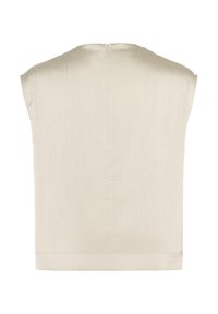 Haut sans manches beige clair avec un tissu lisse et texturé. Présente un col montant et une fermeture éclair au dos. Silhouette simple et carrée.