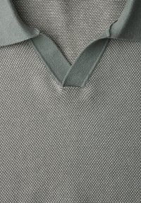 Gros plan sur un pull gris en maille avec un col en V plié et un motif de tissu texturé.