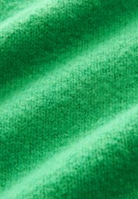 Tessuto verde testurizzato con un morbido motivo a maglia, caratterizzato da elementi in rilievo e tessuti che creano profondità e una qualità tattile.