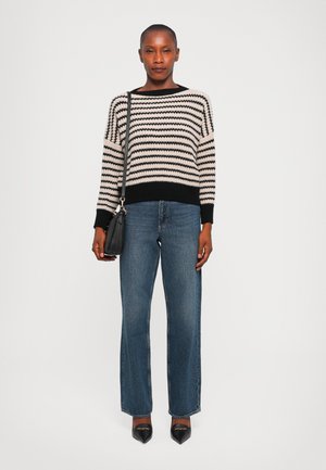 Maglione a righe in nero e crema, con polsini e orlo a coste. Abbinato a jeans blu a vita alta e décolleté neri a punta. Piccola borsa nera.
