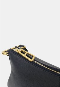 Borsa in pelle blu navy con superficie testurizzata, dotata di chiusura con zip dorata e accessori in metallo dorato, e di forma arrotondata.