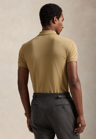 Tan kortärmad pikétröja med texturerad yta. Kombinerad med grå skräddarsydda byxor med bakfickor och bälteshållare.