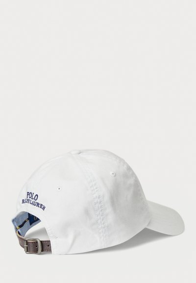 Balta medvilninė beisbolo kepurė su išlenktu brim, išsiuvinėtas "Polo Ralph Lauren" tamsiai mėlyna spalva, reguliuojama ruda odinė juosta gale.
