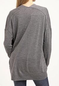 Suéter gris de corte relajado, con cuello en V y mangas ligeramente oversized. Textura suave y detalle de dobladillo acanalado.