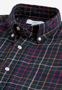 Karierte Hemd in dunklem Marineblau mit roten, grünen und beigen Kästchen. Hergestellt aus weichem Stoff mit weißen Knöpfen und einem Button-Down-Kragen.
