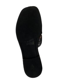 Schwarze Schuhsohle aus strukturiertem Gummi, mit einer glatten Fläche nahe der Ferse und einer geschwungenen Form, die Grip und Stabilität bietet.