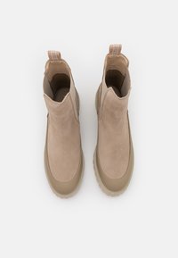 Béžové semišové kotníkové boty s hladkou gumovou podešví, které mají minimalistický design a poutko na patě pro snadné obouvání.